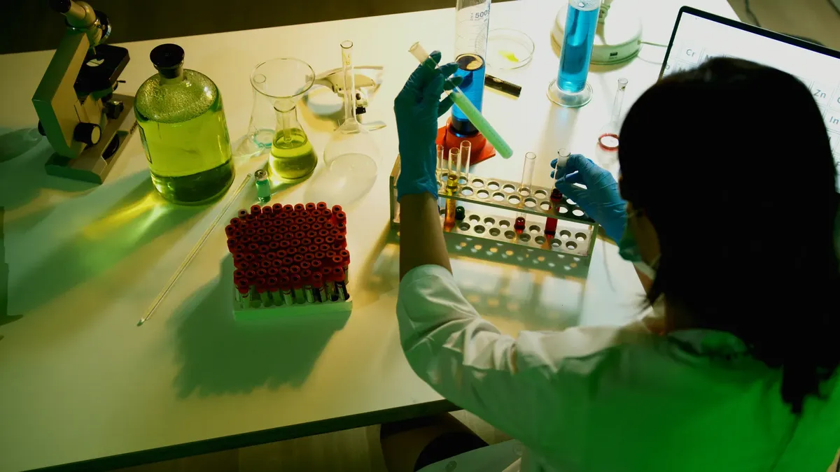 Researcher examines vials in a laboratory setting, engaging in scientific experiments.