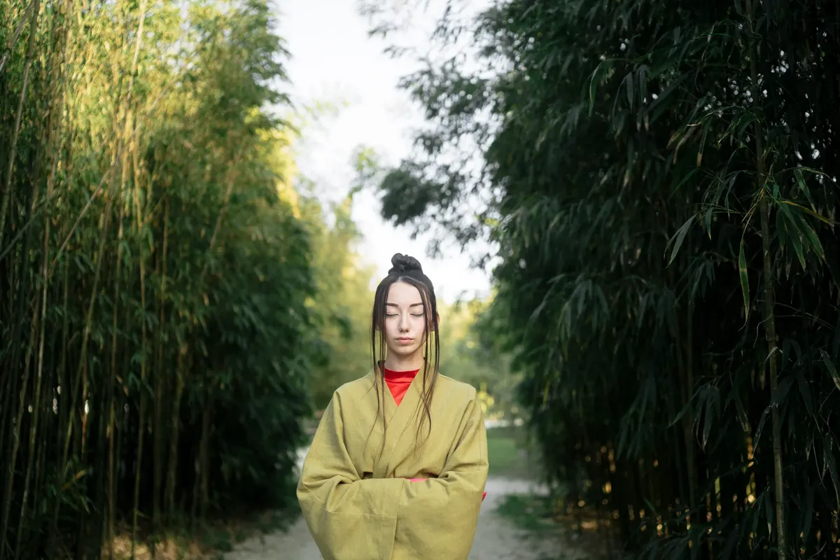 A woman in a kimono meditates in a tranquil bamboo garden, embracing Japanese aesthetics.