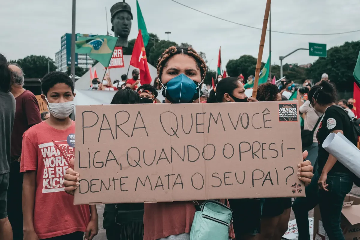 Large gathering in Rio de Janeiro, Brazil, featuring protestors holding signs against government policies.