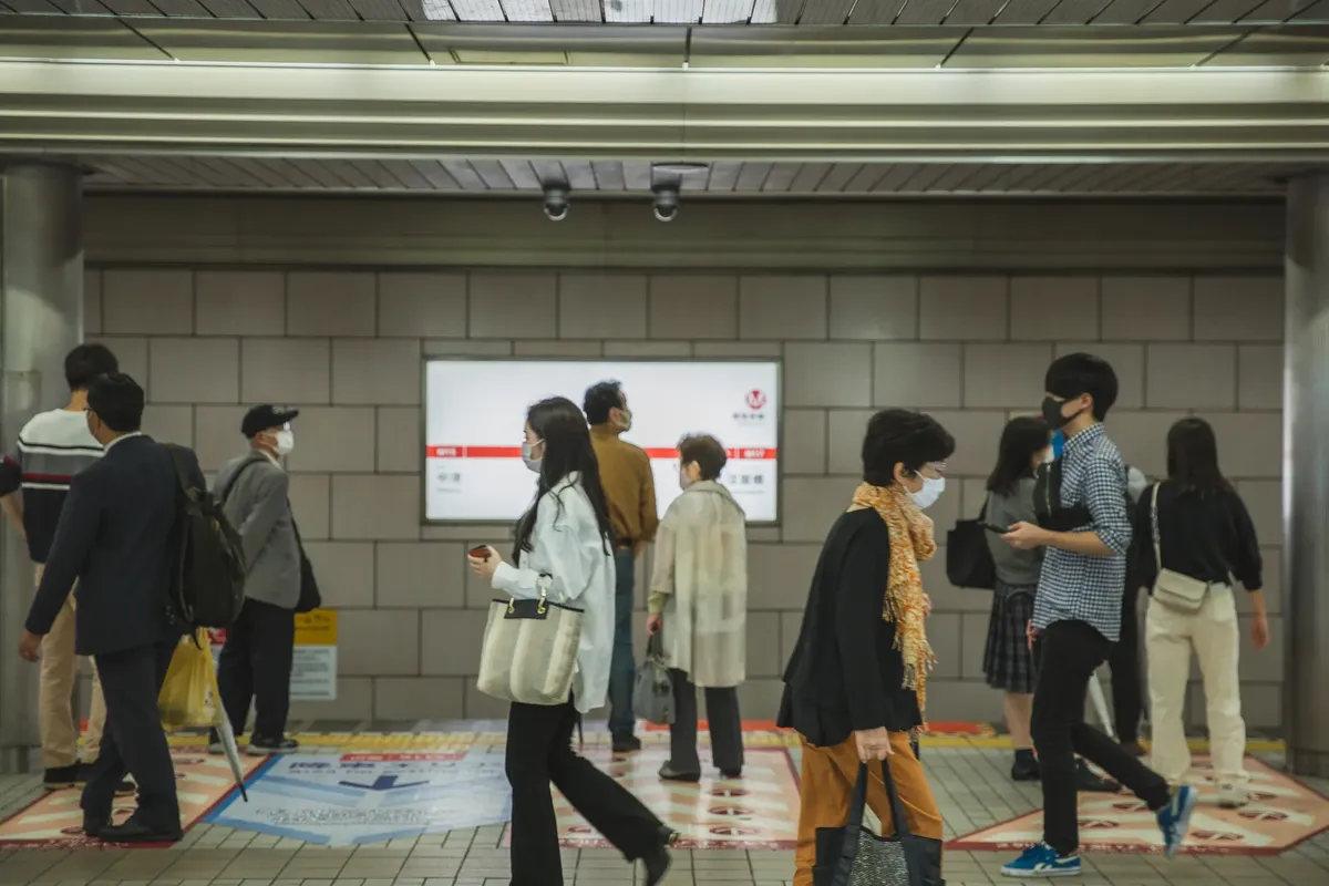 People in protective masks walking in corridor of subway station during coronavirus epidemic