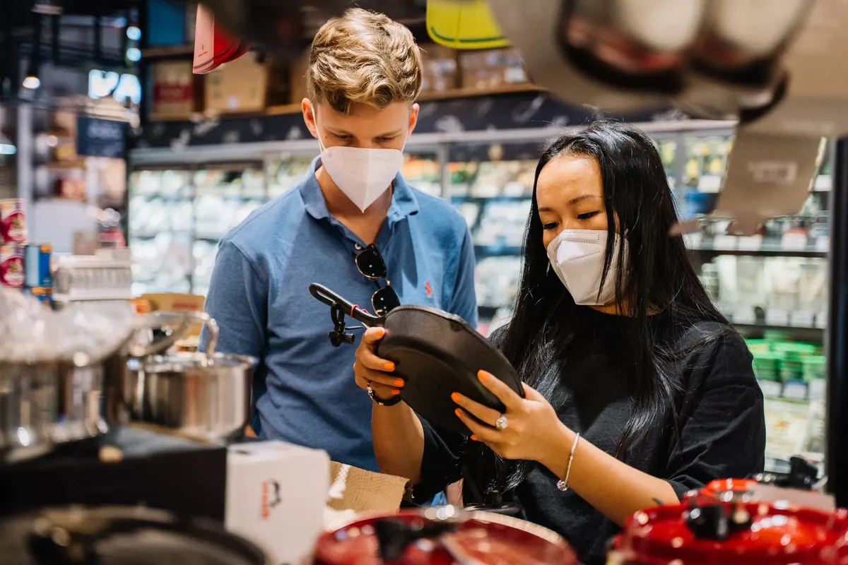A couple wearing masks shopping for kitchenware in a store during the COVID-19 pandemic.
