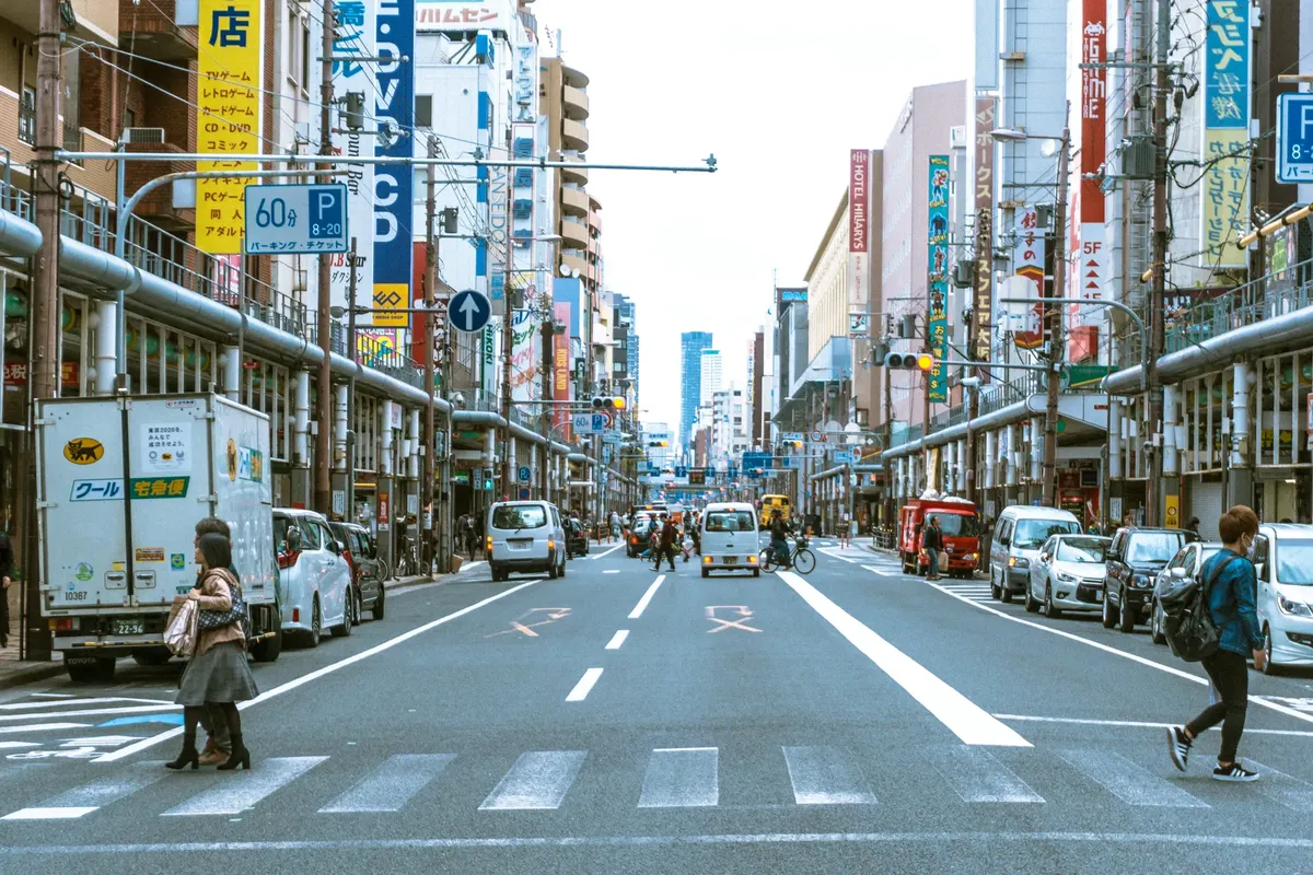 Vibrant urban street scene in Japan with people and vehicles, showcasing city life and Japanese culture.