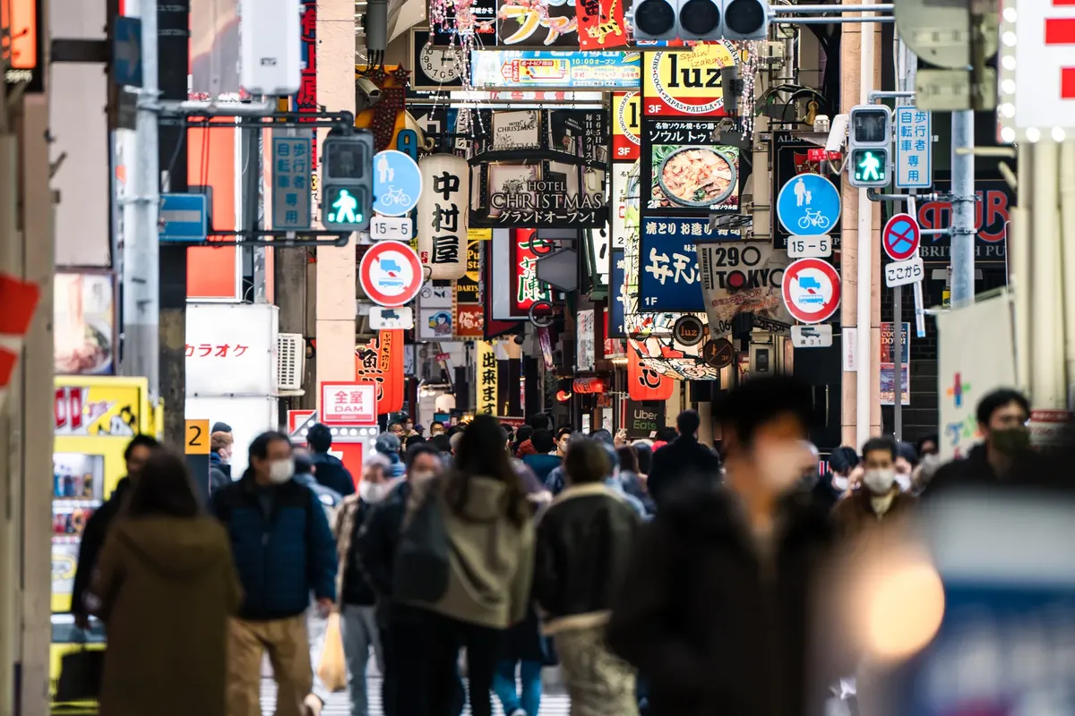 Bustling street in Osaka filled with signs and people, capturing the urban vibrancy of Japan.